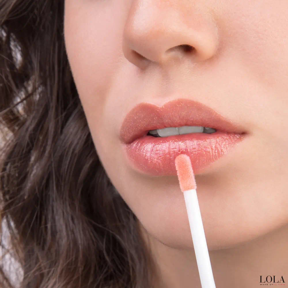 Close-up of a person applying LOLA lip-gloss with a applicator