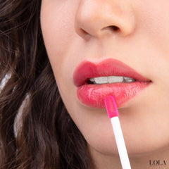 Close-up of a person applying LOLA lip-gloss with a applicator